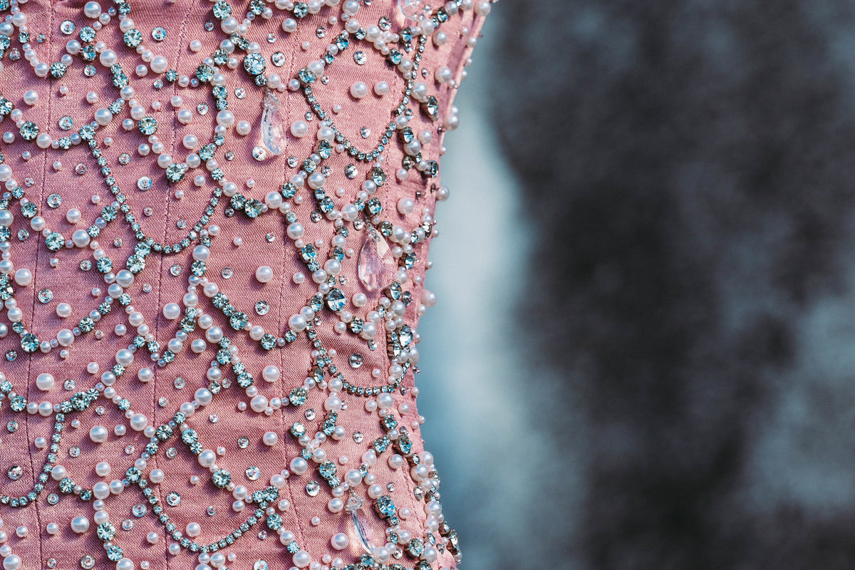 Soft pink corset crafted from 100% viscose, featuring delicate eyelet detailing, custom hand-embroidered detailing and a structured fitted silhouette. Finished with a zip fastening. Designed for romantic eveningwear, special occasions, celebrations and statement winter