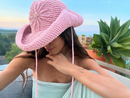 Hand-crocheted baby pink cotton sun hat with beaded sunburst embroidery and an oversized brim, the perfect luxury accessory for summer holidays and beach vacations.