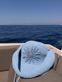 Hand-crocheted baby blue cotton sun hat with beaded sunburst embroidery and an oversized brim, the perfect luxury accessory for summer holidays and beach vacations.