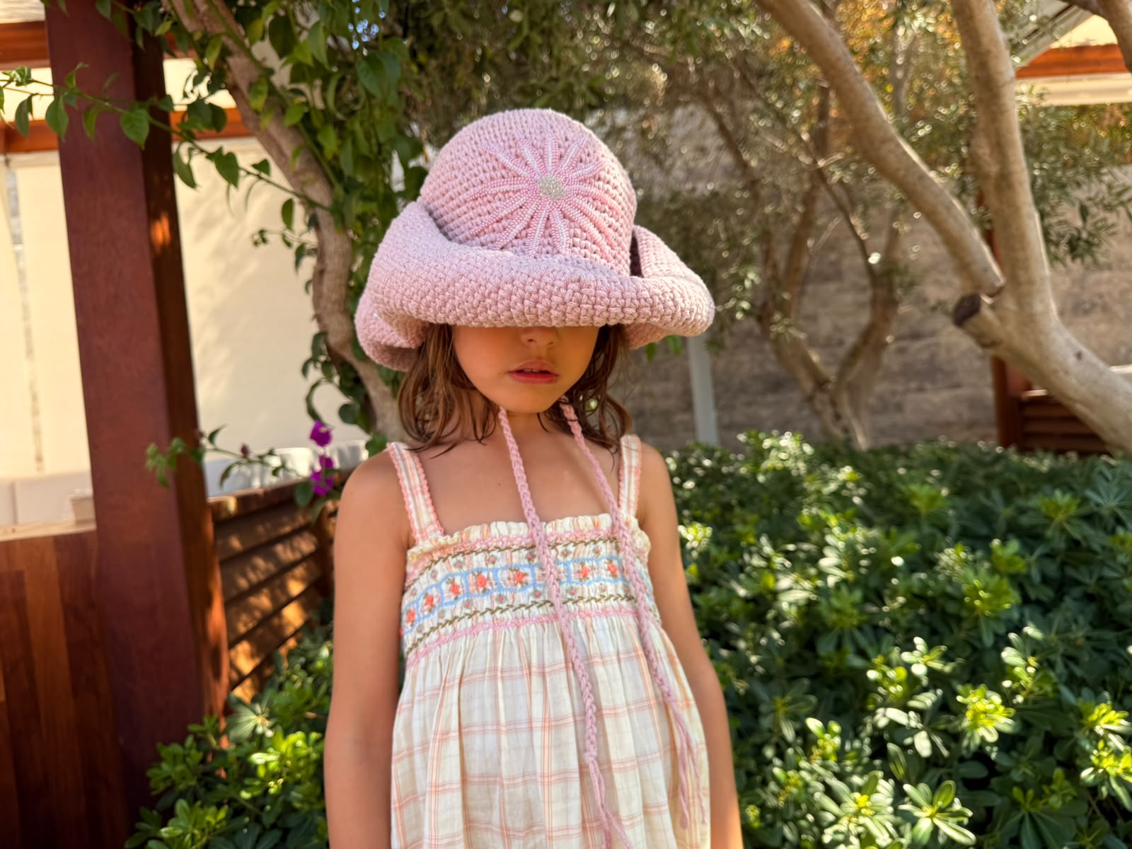 Hand-crocheted baby pink cotton sun hat with beaded sunburst embroidery and an oversized brim, the perfect luxury accessory for summer holidays and beach vacations.